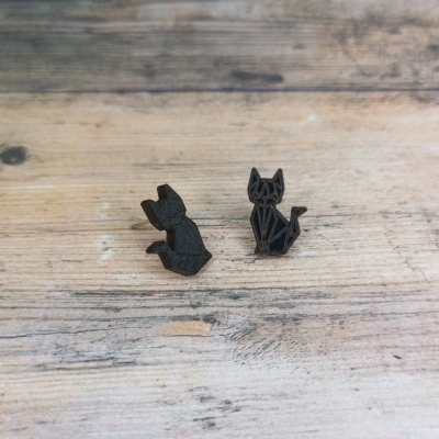 Brincos de gato geométrico em madeira preta colocados sobre madeira clara