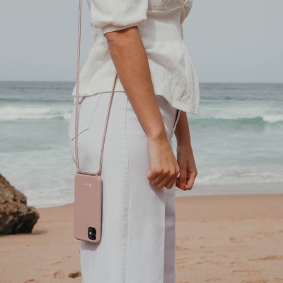 Bolsa pendente rosa claro com fecho usada ao lado do corpo de pessoa na praia