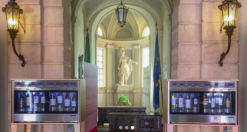 Máquinas automáticas de vinho num espaço clássico com estátua e bandeira da UE