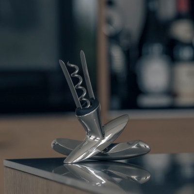 Abridor de vinho metálico prateado sobre superfície preta refletora em cozinha