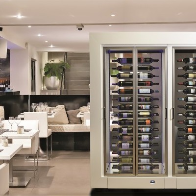 Refrigerador vertical para vinho com portas de vidro e garrafas, em sala de jantar moderna