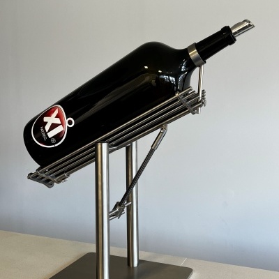Garrafa de vinho preta num suporte metálico prateado