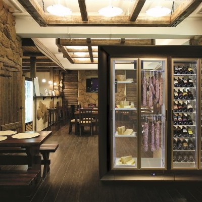 Interior rústico com mesa de madeira e frigorífico expositivo de queijos e enchidos