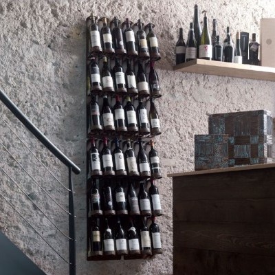 Garrafas de vinho organizadas em parede de pedra com prateleira e balcão de madeira