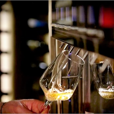 Taça de vinho branco a ser servida por máquina dispensadora metálica