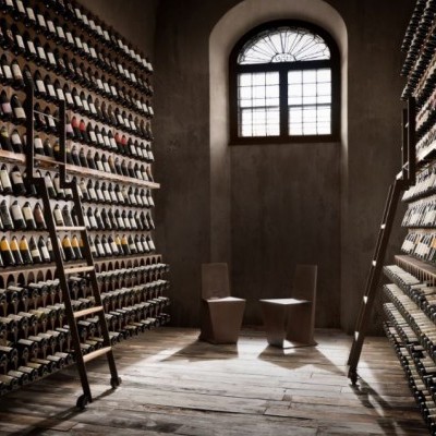 Armazém com prateleiras de vinhos em madeira e janela arqueada