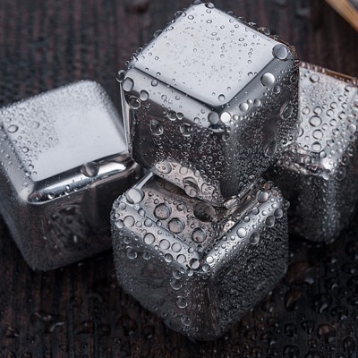 Cubos metálicos prateados com gotas de água sobre superfície escura rugosa