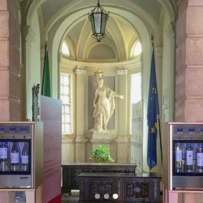 Máquinas automáticas de vinho num espaço clássico com estátua e bandeira da UE