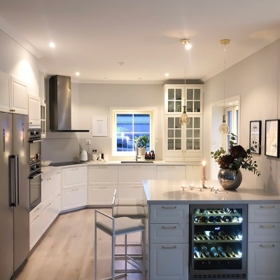 Cozinha moderna branca com ilha e adega iluminada