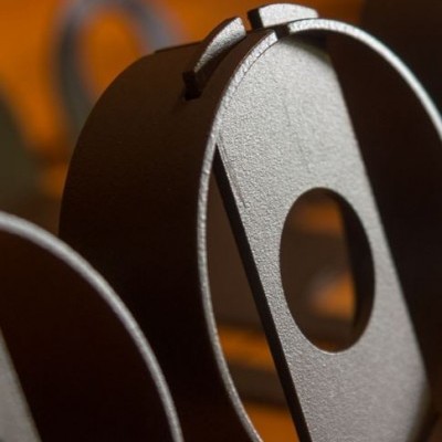 Objeto metálico oval cinza com furo circular e ranhura na parte superior