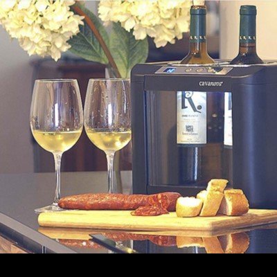 Máquina de servir vinho Cavanova com garrafas, copos e tábua com comida sobre superfície preta