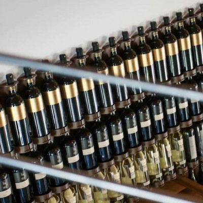 Garrafa de vinho em prateleiras de madeira com rótulos pretos e dourados