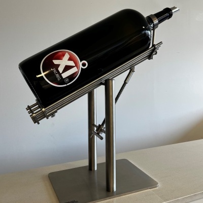 Garrafa preta em suporte metálico sobre superfície clara