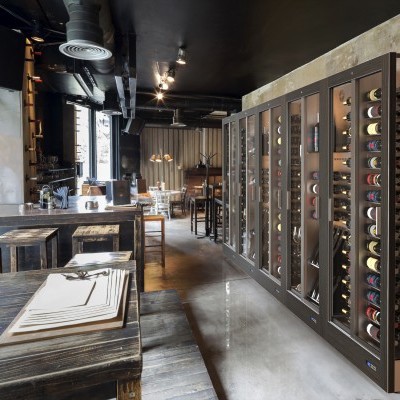 Interior de restaurante com adega e mesas de madeira.