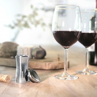 Garrafa de vinho tinto, duas taças com vinho, saca-rolhas e pão numa mesa de madeira