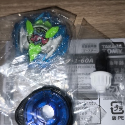 Plastic parts of a spinning top toy in clear packaging on a wooden surface