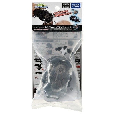 Beyblade acessório preto em embalagem plástica transparente com suporte em cartão branco com texto em japonês