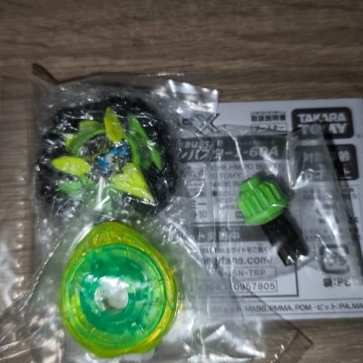 Green and yellow plastic toy parts in clear bags with paper showing TAKARA TOMY text