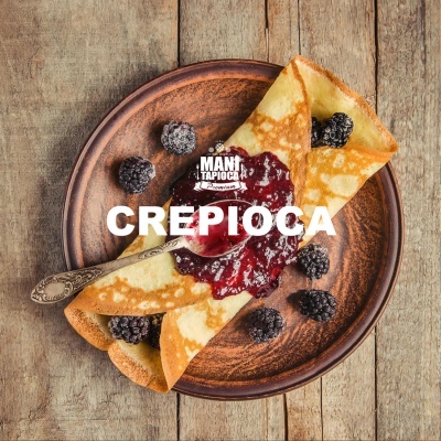 Crepioca com geleia e amoras num prato castanho sobre mesa de madeira