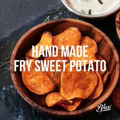 Chips de batata-doce frita numa tigela de madeira com molho branco ao fundo