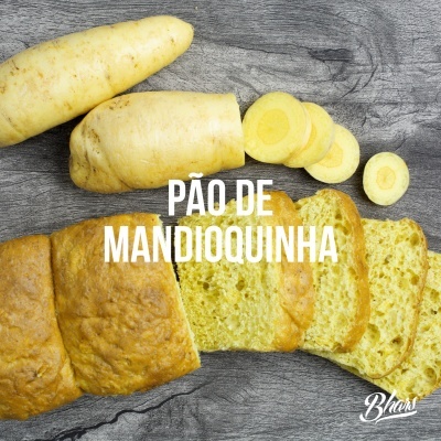Pão de mandioquinha fatiado e mandioquinha crua sobre madeira cinzenta