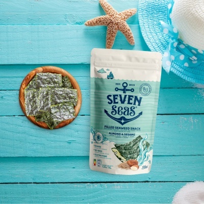 Pacote snack algas Seven Seas amêndoa e sésamo junto a tigela com algas, chapéu azul e estrela-do-mar