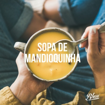 Tigela com sopa de mandioquinha e concha, mãos segurando a tigela