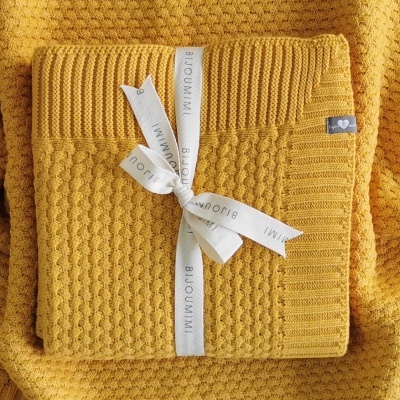 Manta de malha amarela com diferentes padrões de textura, amarrada com fita branca BIJOUXMI