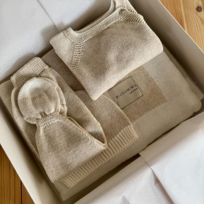 Conjunto de roupa de bebé em malha bege numa caixa branca