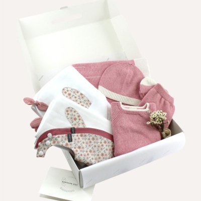 Kit de roupa de bebé rosa e branco em caixa aberta