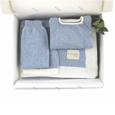 Conjunto de roupa de bebé azul e branco tricotada numa caixa aberta branca