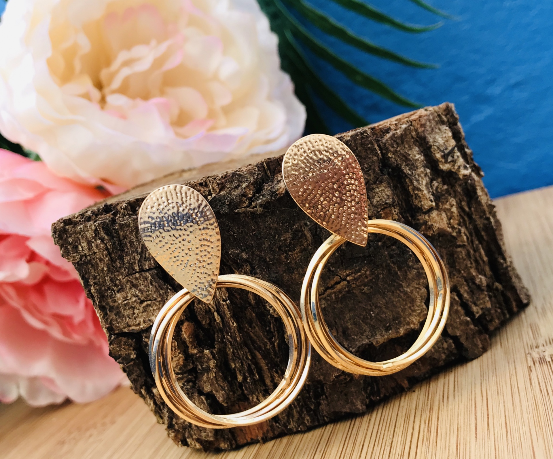 Brincos dourados círculo com textura martelada apoiados em casca de árvore