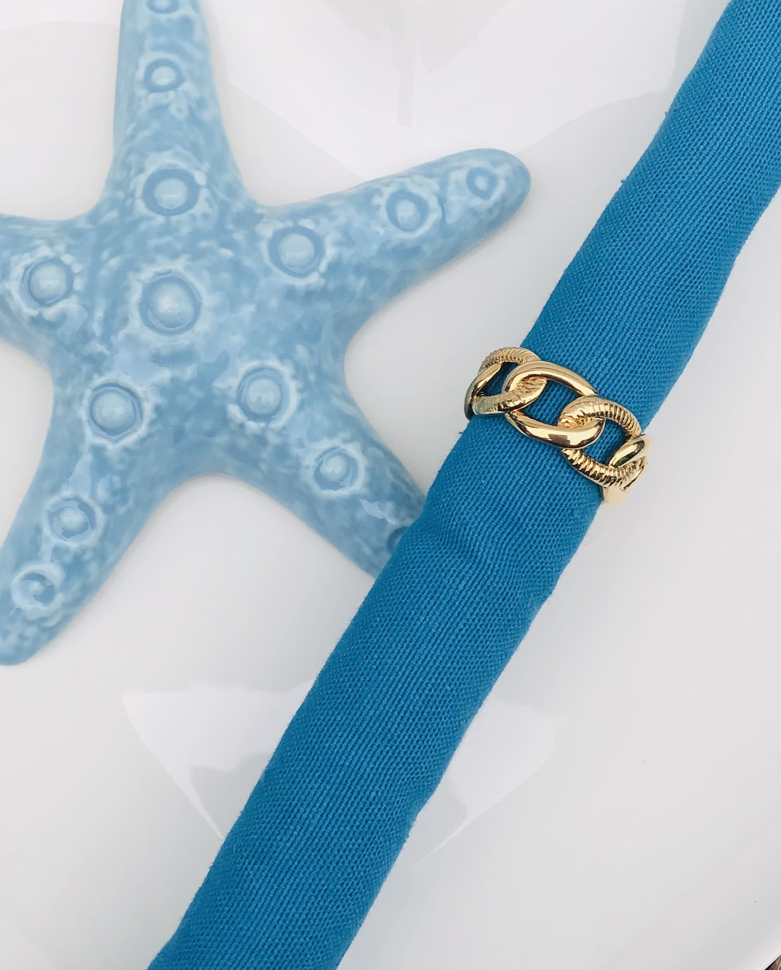 Anel dourado sobre tecido azul com estrela do mar azul clara décor