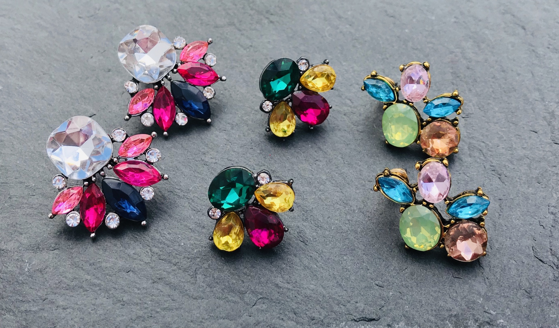 Brincos coloridos com várias pedras em fundo cinza