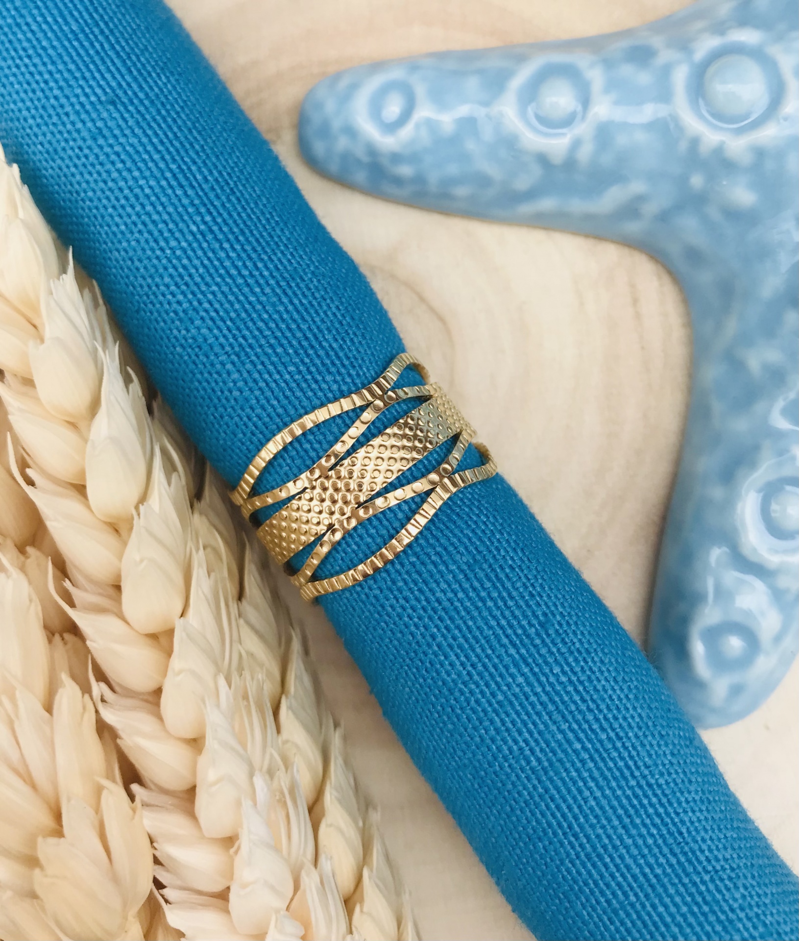 Anel dourado texturizado em toalha azul com estrela do mar azul clara