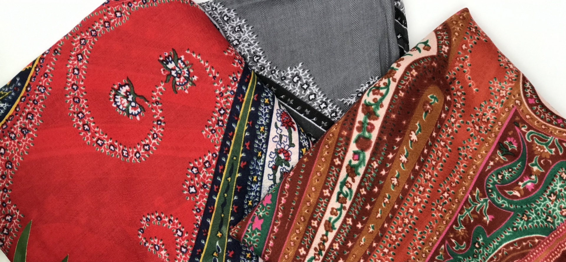 Três lenços com padrões paisley em vermelho, castanho e cinzento