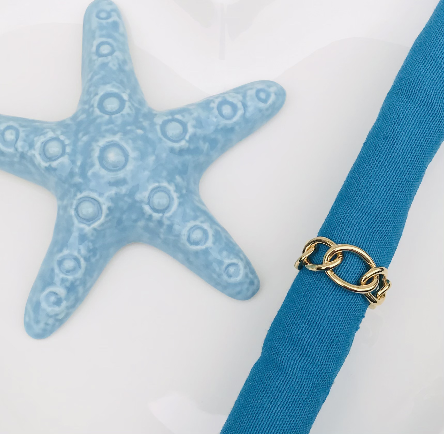 Guardanapo azul com argola dourada e decoração estrela do mar azul