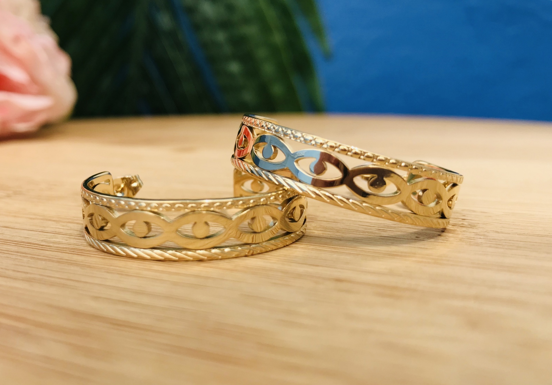 Brincos dourados com padrão de círculos sobre madeira clara