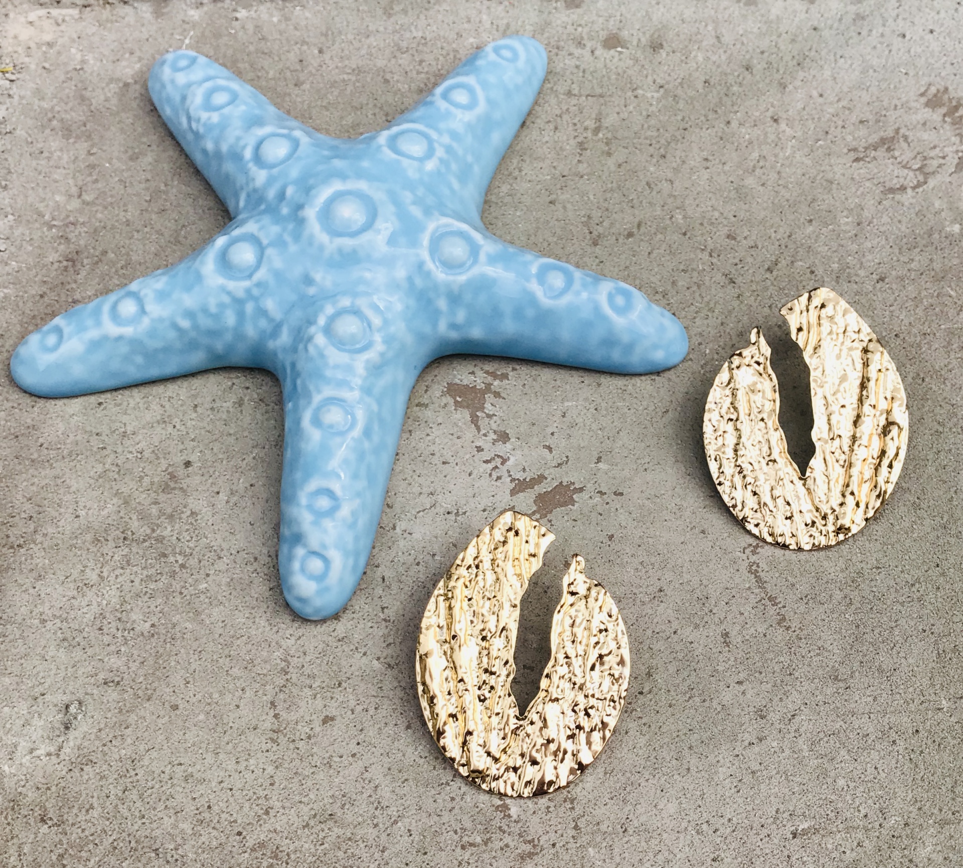 Estrela-do-mar azul em cerâmica e duas peças ovais bege texturizadas sobre superfície cinza