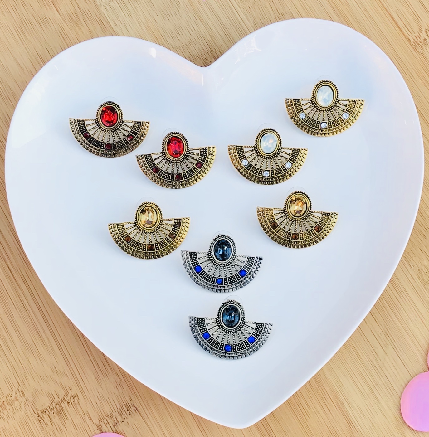 Brincos diversos em forma de leque sobre prato branco em forma de coração