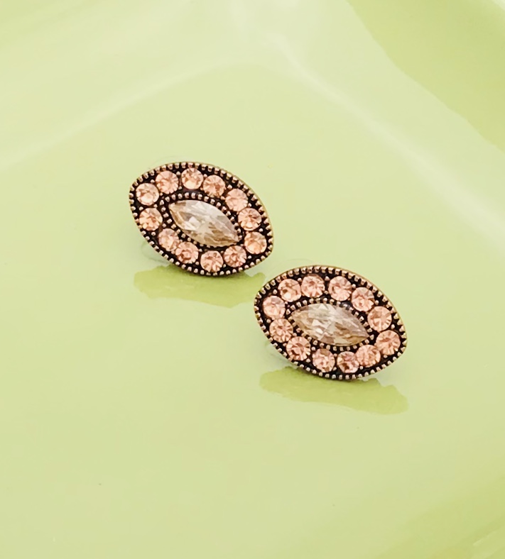 Brincos ovais com pedras translúcidas e cor-de-rosa sobre fundo verde claro