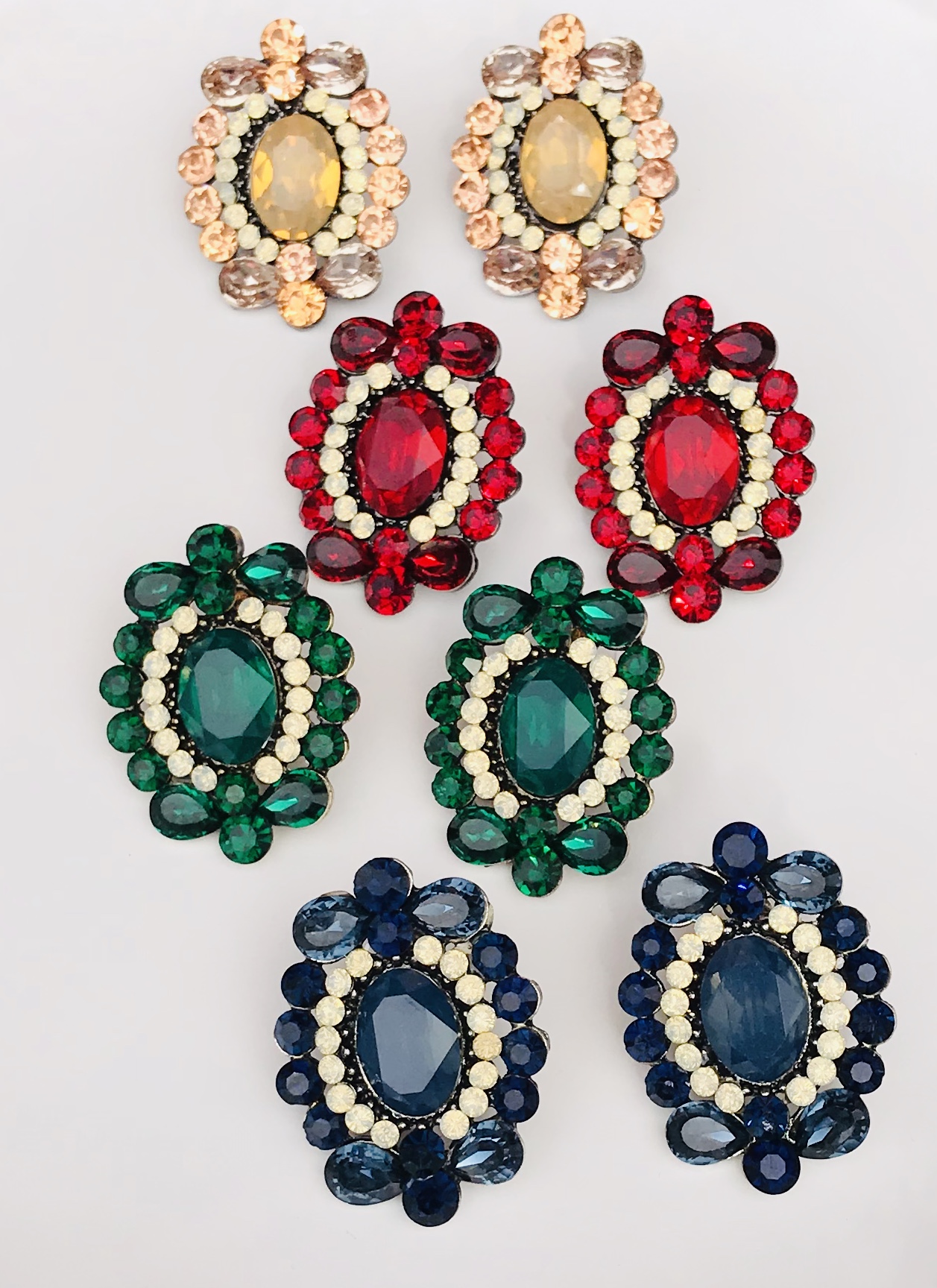 Oito brincos coloridos com pedras grandes e pequenas, organizados em pares sobre fundo branco.