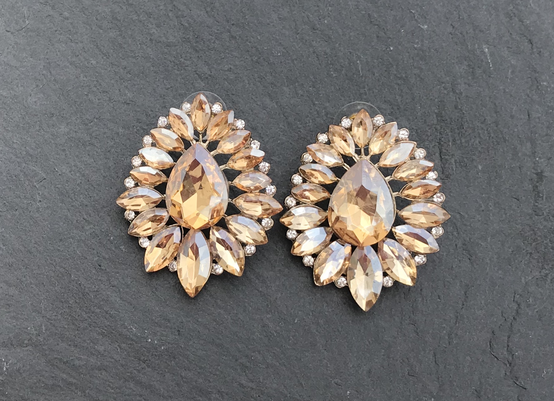 Brincos com cristais amarelos e transparentes em fundo cinza