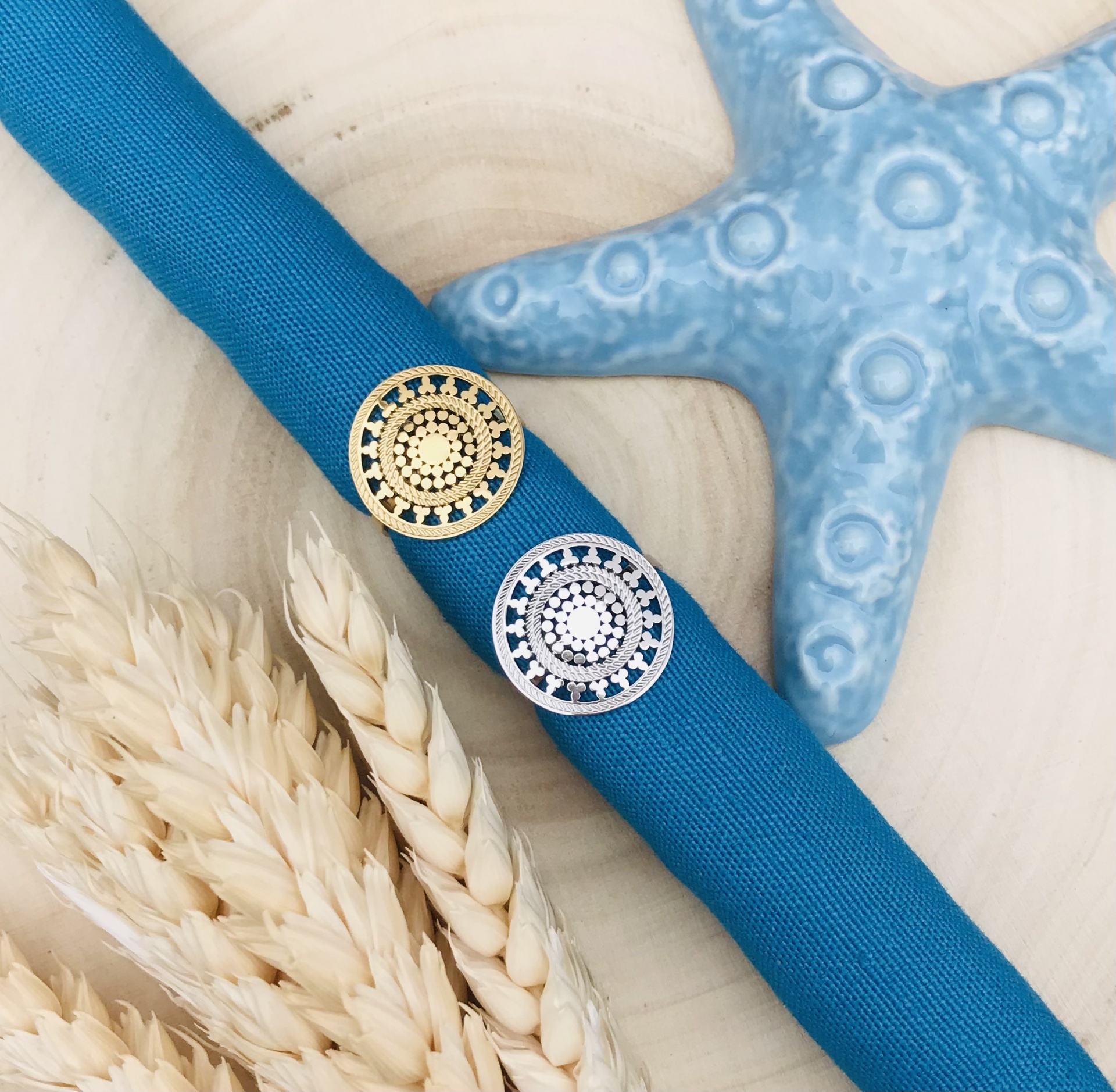 Dois botões decorativos redondos em tecido azul com estrela-do-mar e espigas