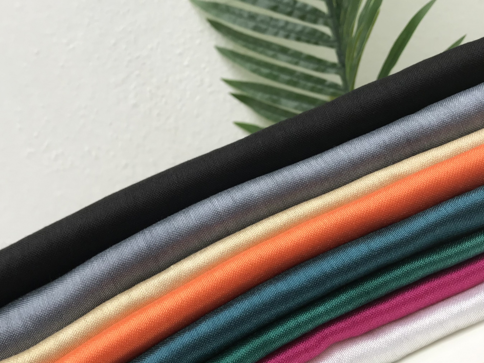 Tecidos coloridos dobrados com textura suave e uma folha verde ao fundo