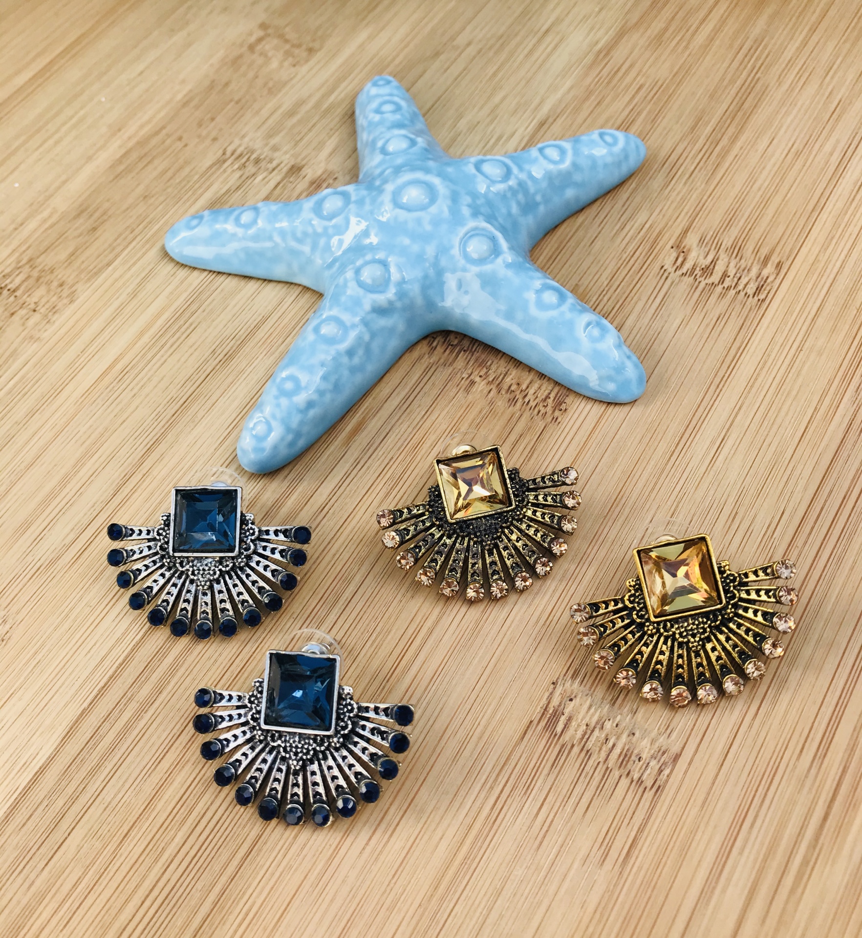 Quatro brincos com pedras coloridas e estrela do mar azul em madeira clara