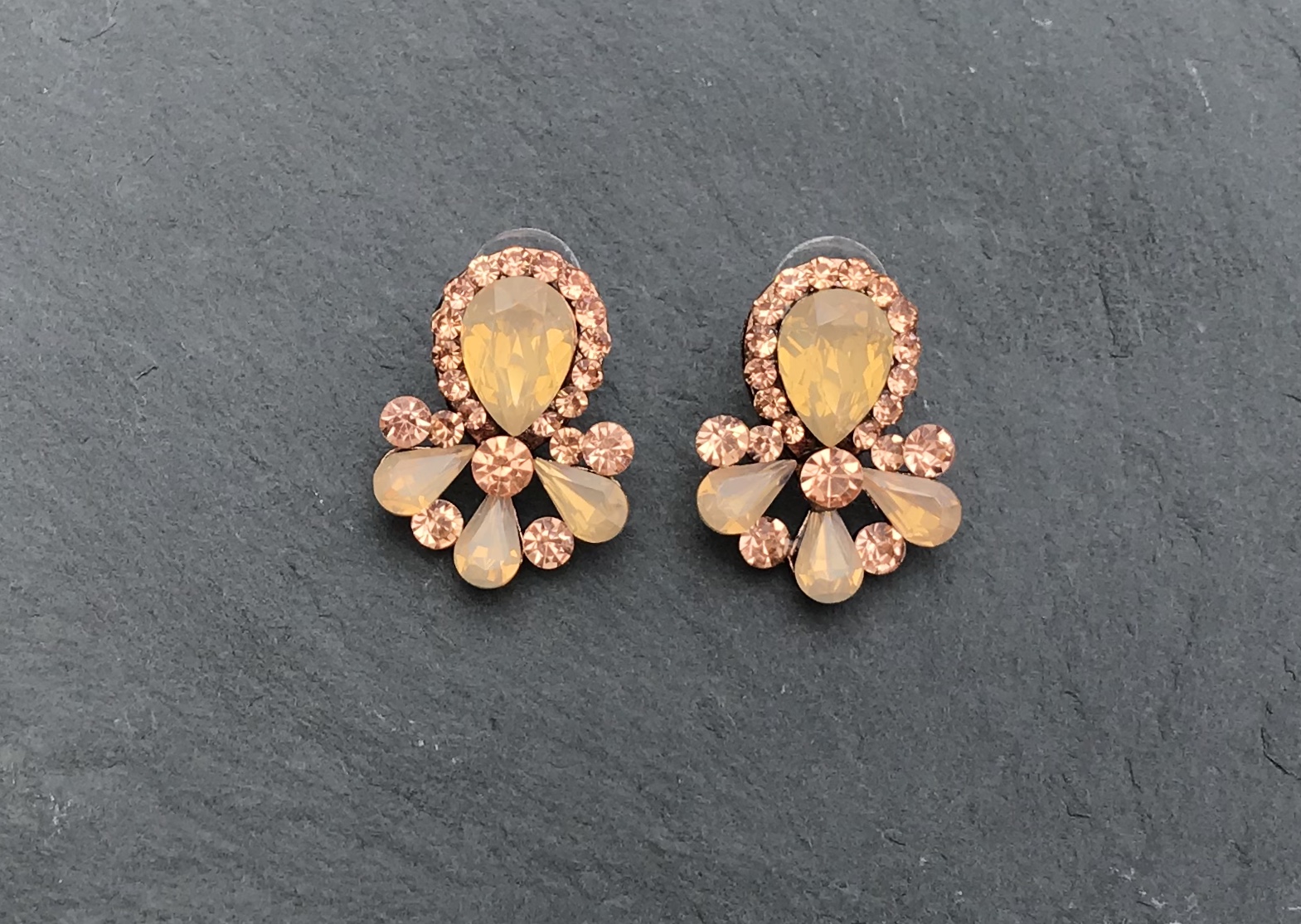 Brincos decorativos com pedras amarelas e castanhas em fundo escuro