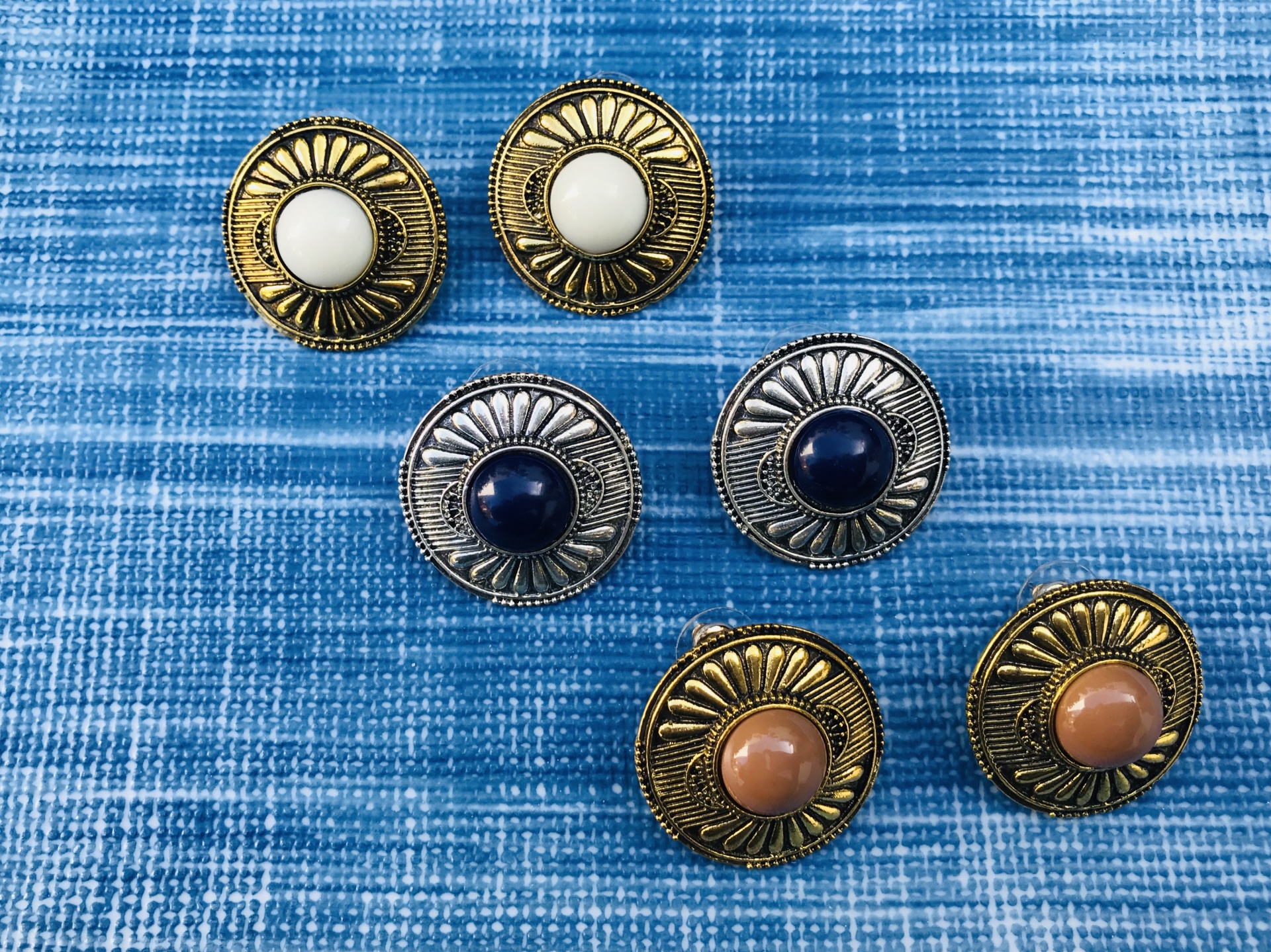 Seis botões redondos metal texturizado com centro colorido sobre tecido azul