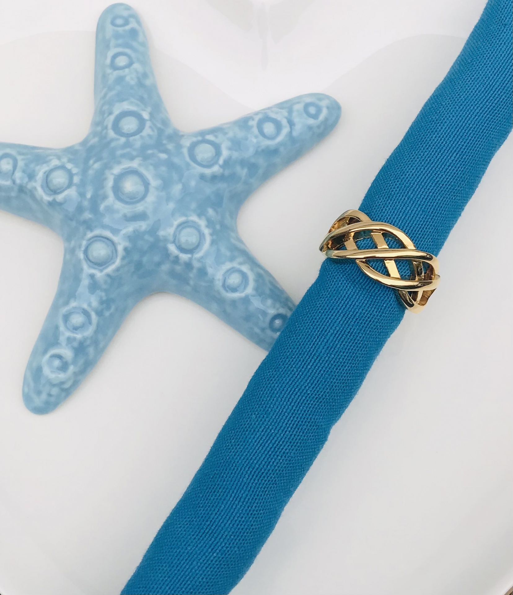Anel dourado entrelaçado com tecido azul e estrela do mar decorativa azul