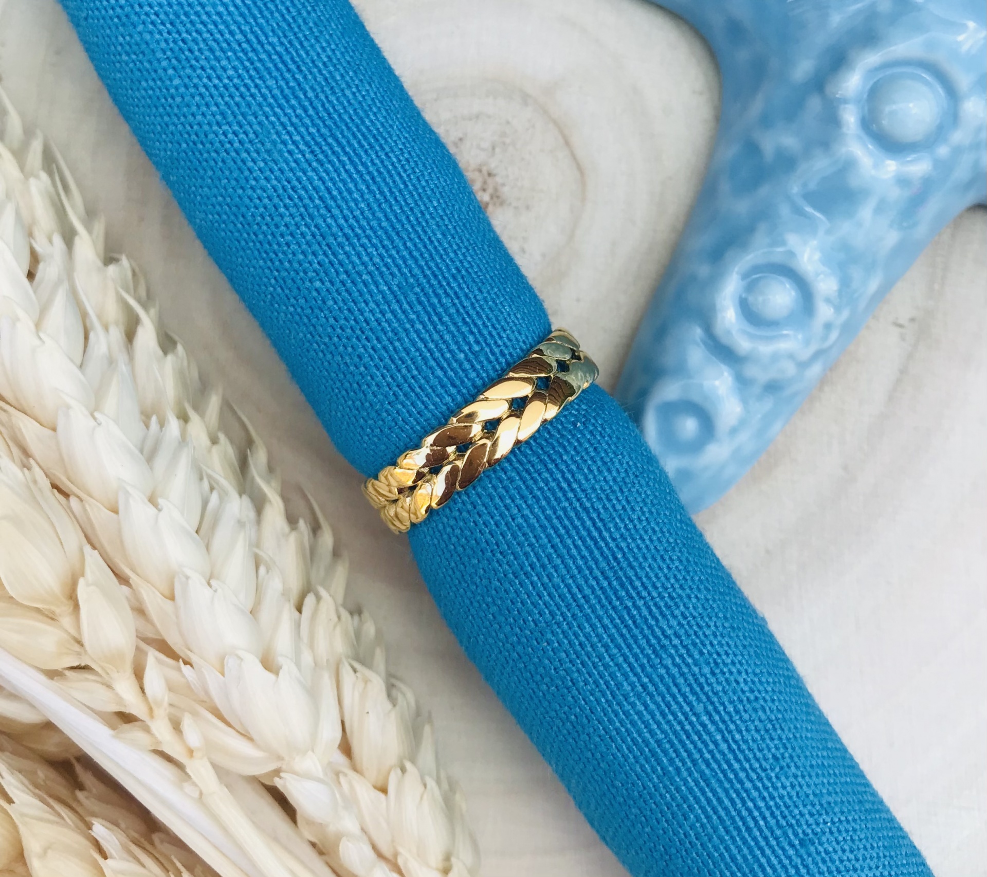 Anel dourado com padrão de escamas e guardanapo azul